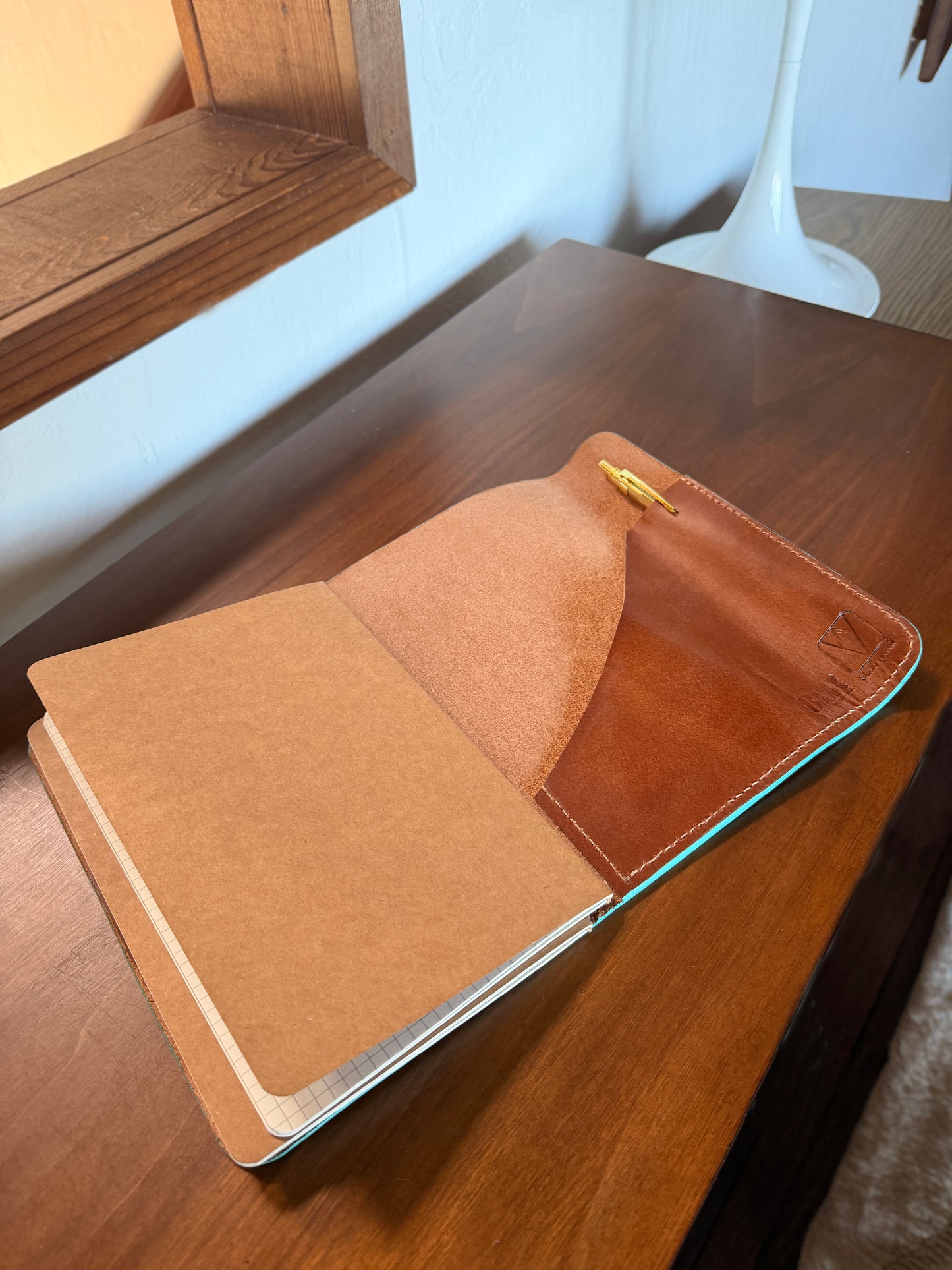 Open leather-bound journal notebook on a wooden surface with a minimal background