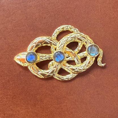 Gold snake buckle with threegemstones on a brown leather background