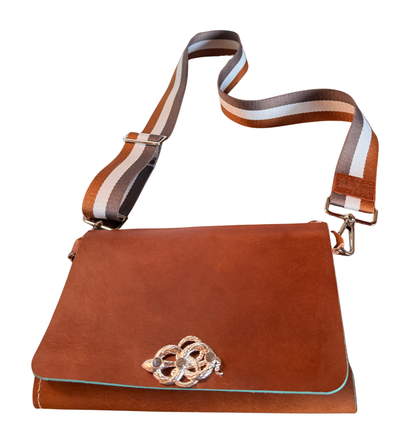 Brown leather wearable travel journal with a decorative snake clasp on a white background