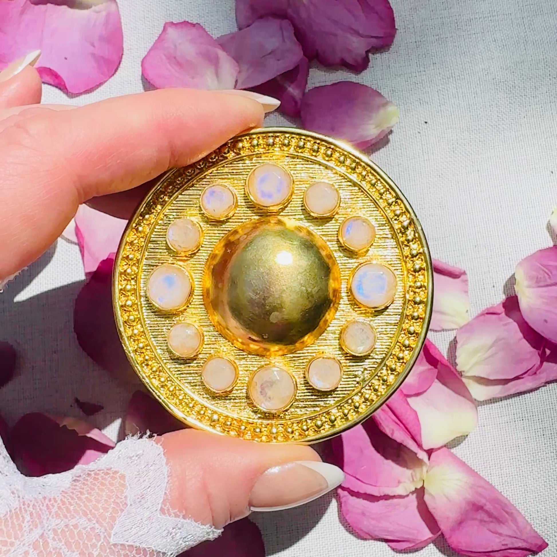 A CUSTOM GOLD ROUND SHAPED BELT BUCKLE WITH FACETED RAINBOW MOONSTONE ACCENTS 